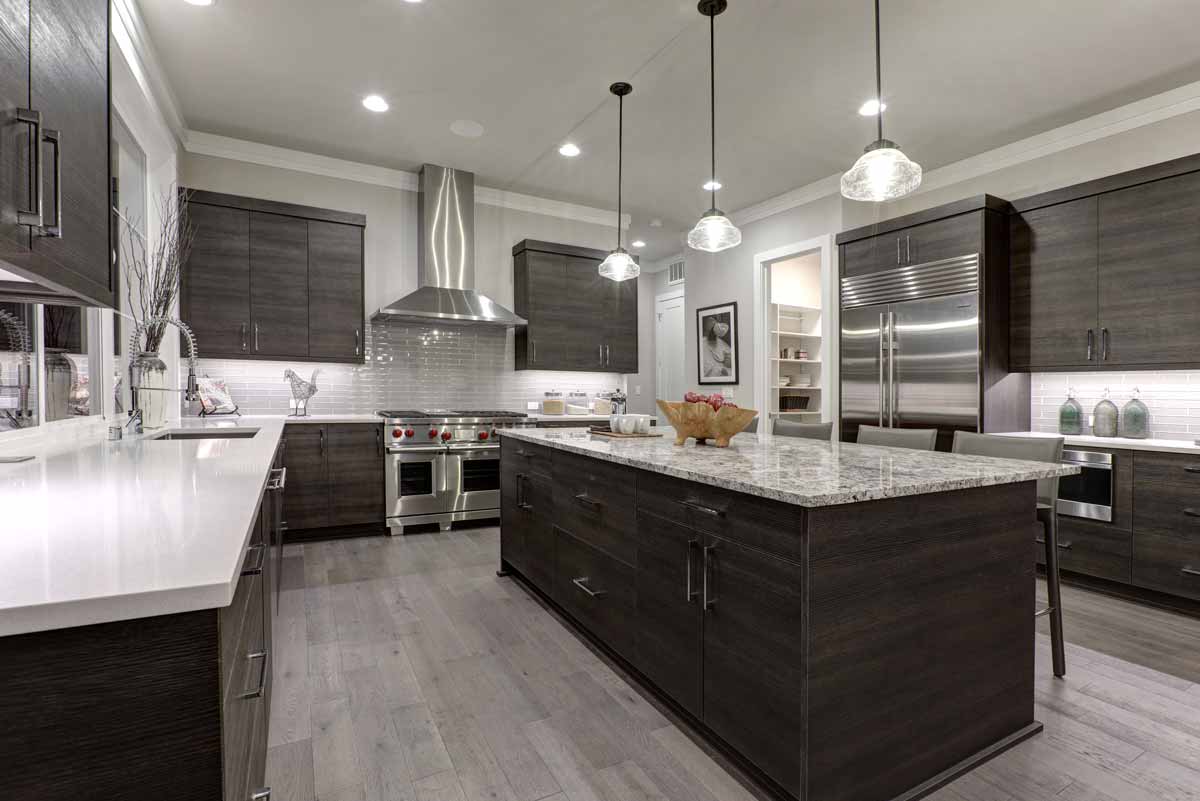 A kitchen with granite countertops, dark wood cabinets, and luxury appliances